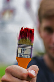 Schemenhaft erkennbarer Maler, in der Hand ein Pinsel mit roter Lackfarbe Schemenhaft erkennbarer Maler, in der Hand ein Pinsel mit roter Lackfarbe