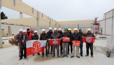 Bauarbeiter in einem Hallen-Rohbau, mit IG BAU-Flaggen