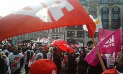 Demonstranten mit ver.di-Fahnen, im Vordergrund eine IG BAU-Flagge Demonstranten mit ver.di-Fahnen, im Vordergrund eine IG BAU-Flagge