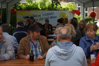 Rund 30 Menschen an Biertischen, im Hintergrund ein Transparent mit der Aufschrift: "Wir haben es verdient - gleiche Löhne Ost und West!" Rund 30 Menschen an Biertischen, im Hintergrund ein Transparent mit der Aufschrift: "Wir haben es verdient - gleiche Löhne Ost und West!"