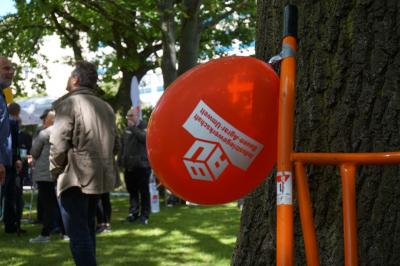 Luftballon mit IG BAU-Aufdruck, im Hintergrund mehrere Personen, die sich unterhalten Luftballon mit IG BAU-Aufdruck, im Hintergrund mehrere Personen, die sich unterhalten
