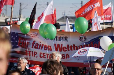 Menschen, Fahnen, Luftballons, in der Mitte ein IG BAU-Transparent mit der Aufschrift "Für fairen Welthandel" und durchgestrichenen "TTIP"-Symbolen. Menschen, Fahnen, Luftballons, in der Mitte ein IG BAU-Transparent mit der Aufschrift "Für fairen Welthandel" und durchgestrichenen "TTIP"-Symbolen.