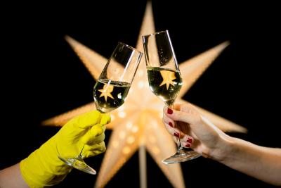 Beleuchteter Weihnachtsstern, davor zwei Sektgläser, die "anstoßen"