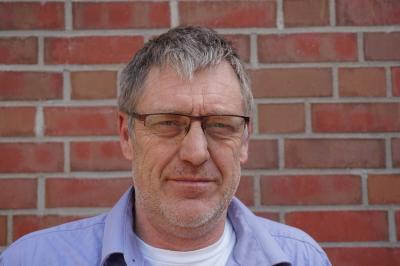 Portraitaufnahme von Achim Bartels for einer gemauerten Wand.