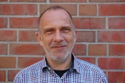 Portraitaufnahme Uwe Nack vor einer gemauerten Wand. Portraitaufnahme Uwe Nack vor einer gemauerten Wand.