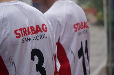 Zwei Rücken mit der Aufschrift "STRABAG Team Work" Zwei Rücken mit der Aufschrift "STRABAG Team Work"