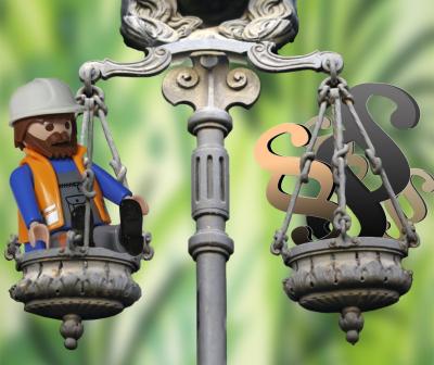 Playmobil-Arbeiter in einer Waagschale, auf der anderen Seite der Waage das "Paragraphen"-Zeichen Playmobil-Arbeiter in einer Waagschale, auf der anderen Seite der Waage das "Paragraphen"-Zeichen