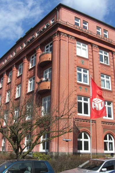 Das Bundeshaus der IG BAU in Hamburg - fünf Stockwerke, roter Backstein, davor rote Fahnen der IG BAU. Das Bundeshaus der IG BAU in Hamburg - fünf Stockwerke, roter Backstein, davor rote Fahnen der IG BAU.