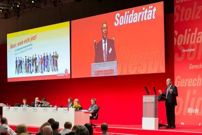 Bühne ganz in rot gehalten, mit großen Videoleinwänden. Vorne rechts der Bundesvorsitzende Robert Feiger am Redepult. Bühne ganz in rot gehalten, mit großen Videoleinwänden. Vorne rechts der Bundesvorsitzende Robert Feiger am Redepult.