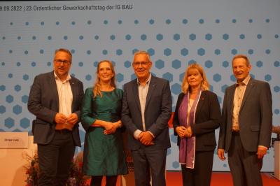 Die Mitglieder des Bundesvorstands nach ihrer Wahl, von links nach rechts: Carsten Burckhardt, Nicole Siems, Robert Feiger, Ulrike Laux, Harald Schaum. Im Hintergrund eine Leinwand mit unterschiedlich großen blauen Punkten auf weißem Hintergrund. Und klei Die Mitglieder des Bundesvorstands nach ihrer Wahl, von links nach rechts: Carsten Burckhardt, Nicole Siems, Robert Feiger, Ulrike Laux, Harald Schaum. Im Hintergrund eine Leinwand mit unterschiedlich großen blauen Punkten auf weißem Hintergrund. Und klei