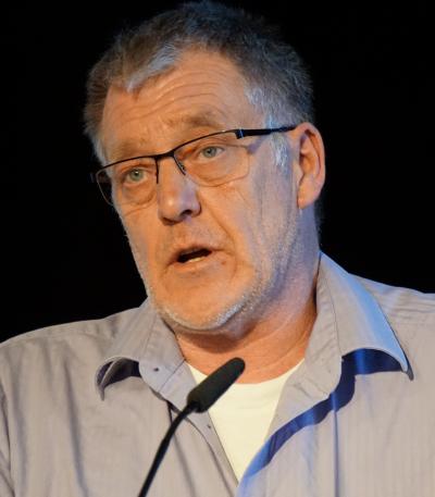 Achim Bartels in hellblauem Hemd am Mikrofon. Der Hintergrund ist schwarz. Achim Bartels in hellblauem Hemd am Mikrofon. Der Hintergrund ist schwarz.