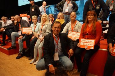 André Grundmann, Regionalleiter der IG BAU Nord, hockend vor gut einem Dutzend Delegierten - alle tragen ihre Delegiertenausweise an roten Bändern um den Hals. André Grundmann, Regionalleiter der IG BAU Nord, hockend vor gut einem Dutzend Delegierten - alle tragen ihre Delegiertenausweise an roten Bändern um den Hals.