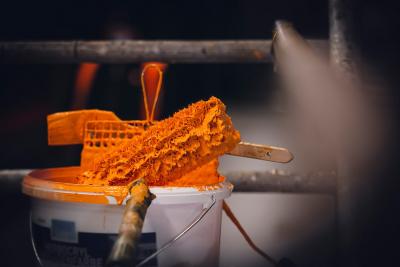 Ein Eimer mit orange-brauner Farbe mit Farbrolle und Pinsel darin. Ein Eimer mit orange-brauner Farbe mit Farbrolle und Pinsel darin.