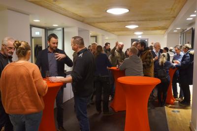 Einige Dutzend Menschen an rot überzogenen Stehtischen im Gespräch. Einige Dutzend Menschen an rot überzogenen Stehtischen im Gespräch.