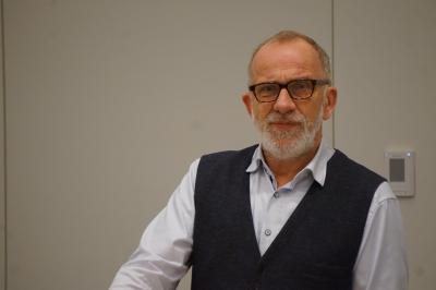 Mann mit Brille, Dreitagebart und dunklem Jackett vor hellem Hintergrund. Mann mit Brille, Dreitagebart und dunklem Jackett vor hellem Hintergrund.