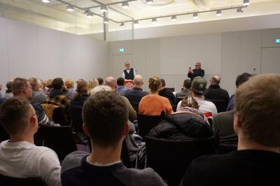 Einige Dutzend Menschen auf Stühlen. Im Hintergrund Redner Uwe Nack. Einige Dutzend Menschen auf Stühlen. Im Hintergrund Redner Uwe Nack.