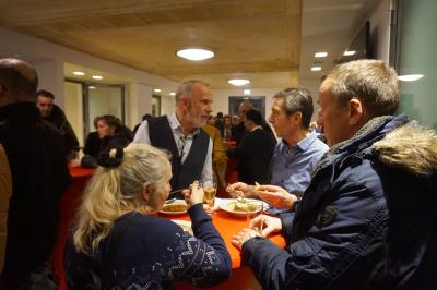 Mehrere Personen im Gespräch an einem Stehtisch. Im Hintergrund weitere Menschen. Mehrere Personen im Gespräch an einem Stehtisch. Im Hintergrund weitere Menschen.